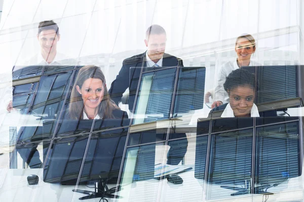 Multietniske Forretningsfolk Som Bruker Stasjonære Datamaskiner Sett Gjennom Glass – stockfoto