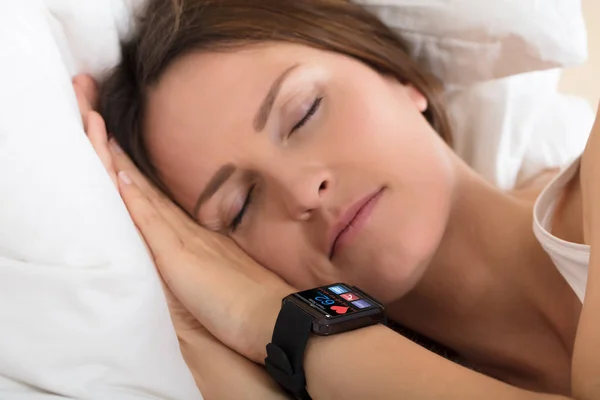 Женщина спит с умными часами, показывая частоту сердцебиения — стоковое фото