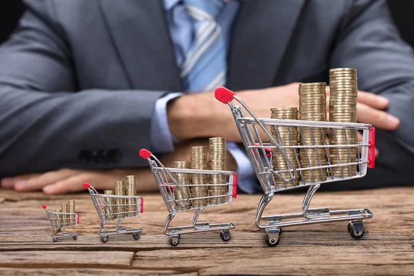 Homme d'affaires avec des pièces dans des chariots d'achat — Photo