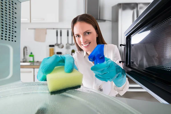 Mujer limpieza microondas — Foto de Stock
