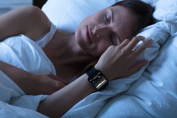 Mujer durmiendo con reloj inteligente — Foto de Stock