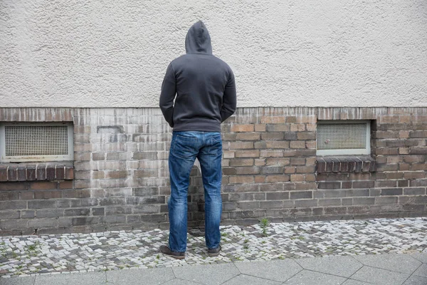 Man In kap plassen op muur — Stockfoto