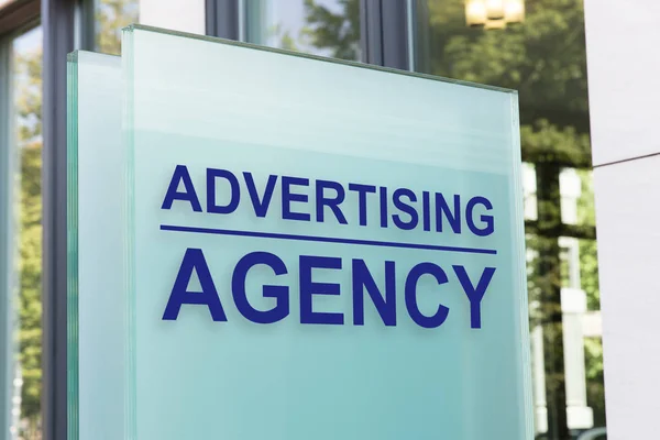 Assinatura de agência de publicidade em placa de vidro — Fotografia de Stock