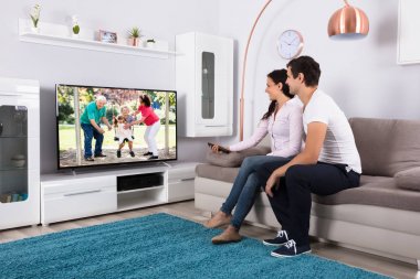 Film televizyonda izlerken kanepede oturan genç Çift