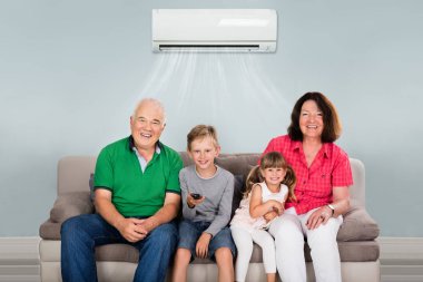 Mutlu çok nesil aile evde Klima altında televizyon izlerken iki çocuklu