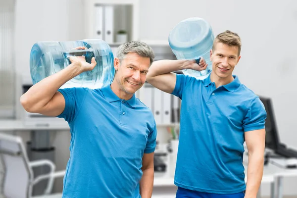 Homens de entrega transportando garrafas de água — Fotografia de Stock
