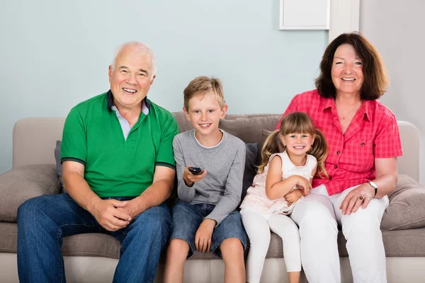 Šťastné Prarodiče Vnoučaty Sedí Gauči Obývacím Pokoji Sledování Televize — Stock fotografie
