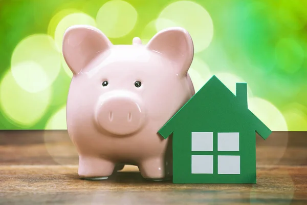 Piggybank e modelo de casa verde — Fotografia de Stock