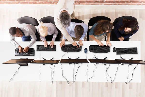 Erkek öğretmen bilgisayar sınıftaki yardımcı yükseltilmiş görünümünü