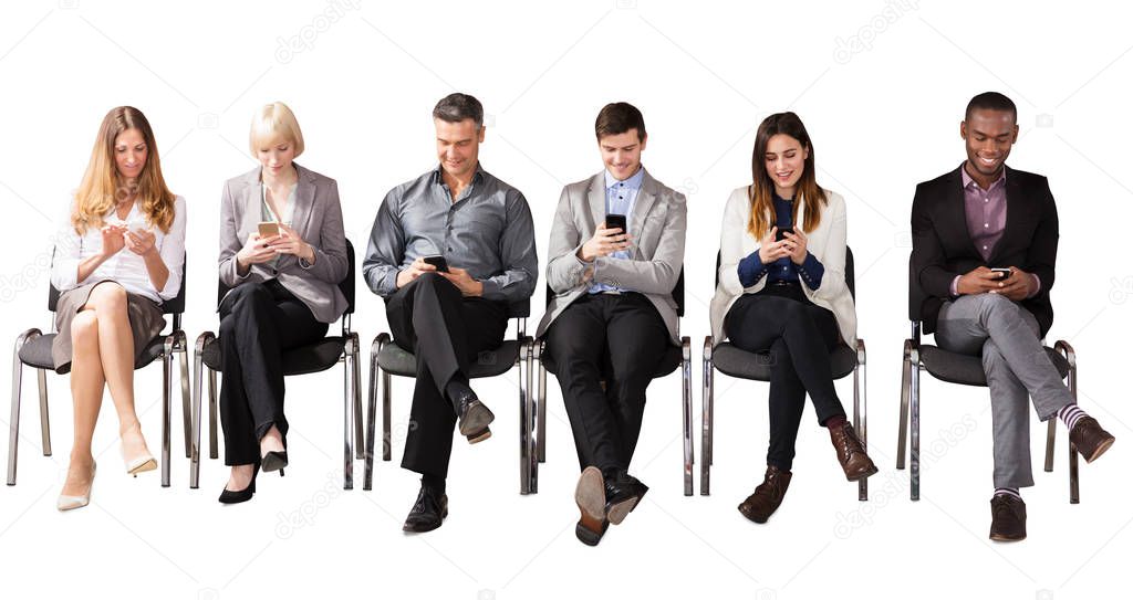 Group Of Multi Ethnic Business People Sitting On Chair Using Cell Phone Against White Background