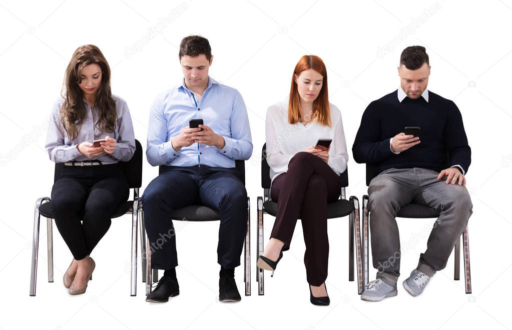 Group Of Multi Ethnic Business People Sitting On Chair Using Cell Phone Against White Background