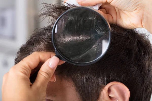 Дерматолог проверяет волосы пациента — стоковое фото