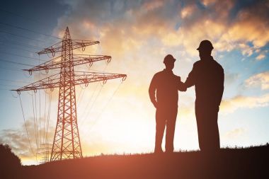 İki mühendis karşı dramatik gökyüzü elektrik pilon elini sıkarken silüeti