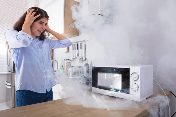 Mulher olhando para o forno de microondas — Fotografia de Stock