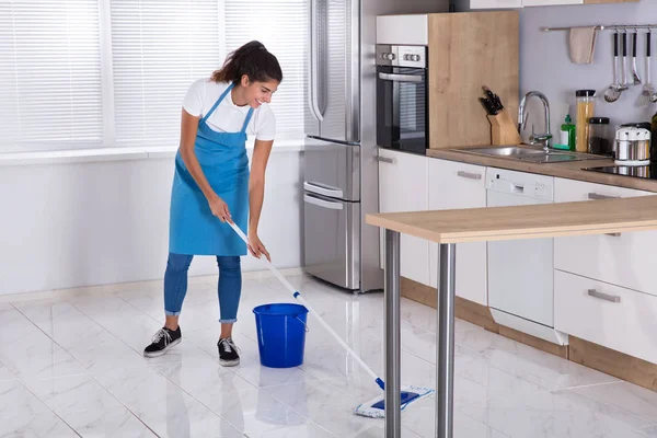 Жінка прибирає підлогу з мопедом — стокове фото