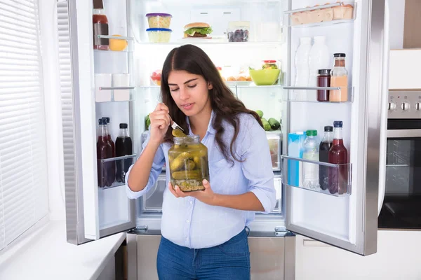 Mujer joven comiendo pepinillos — Foto de Stock