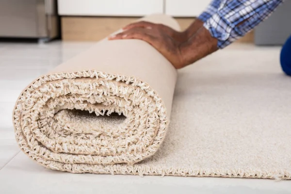 Werknemer handen rollend tapijt — Stockfoto