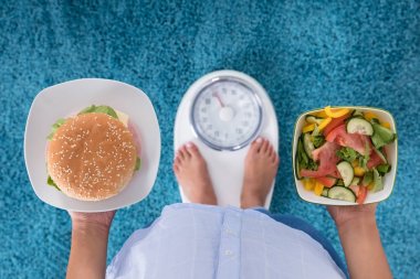 Burger ve salata tutan kişi 