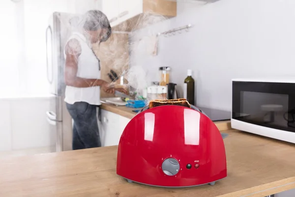 Красный тостер с горящим тостом — стоковое фото
