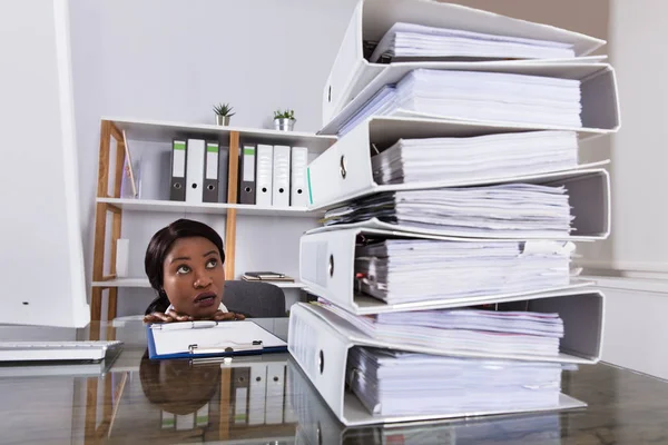 Kobieta, patrząc na stosie folderów na biurko — Zdjęcie stockowe
