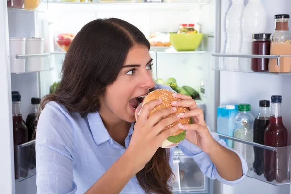 Šťastná žena jíst hamburger — Stock fotografie