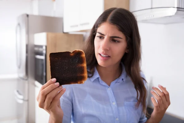 Женщина смотрит на сгоревший тост — стоковое фото