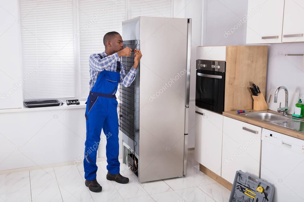 Serviceman Working On Fridge 