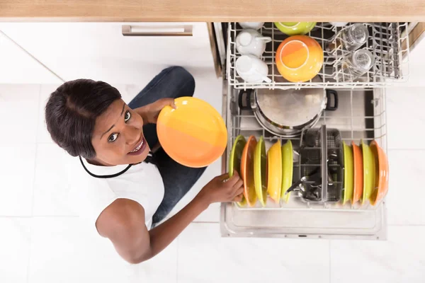 Женщина расставляет тарелки в посудомоечной машине — стоковое фото