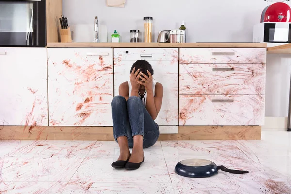 Женщина, сидящая на полу кухни — стоковое фото