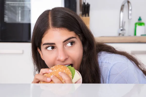 Mujer comiendo hamburguesa en secreto —  Fotos de Stock