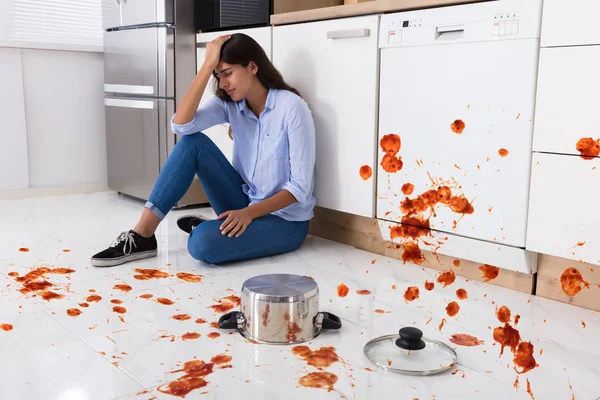 Vrouw zittend op de keukenvloer — Stockfoto