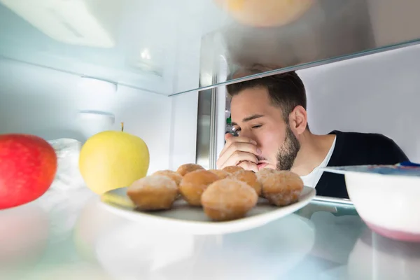 Человек забирает еду из холодильника — стоковое фото