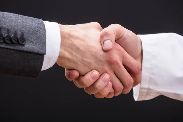 Доктор и бизнесмен пожимают руки — стоковое фото