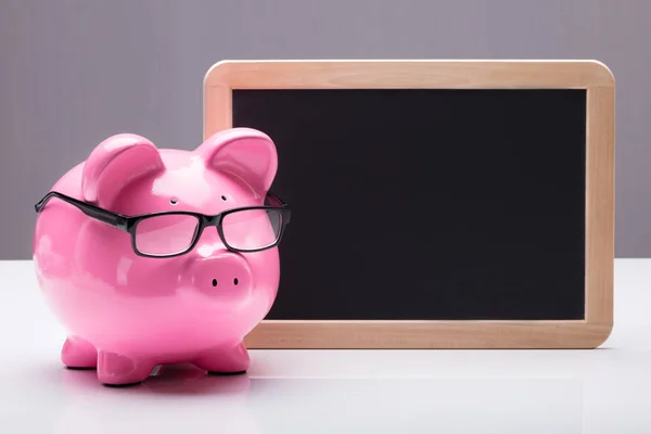 Piggybank com óculos perto da ardósia — Fotografia de Stock