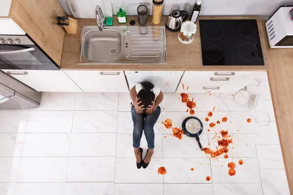 Mulher sentada no chão da cozinha — Fotografia de Stock