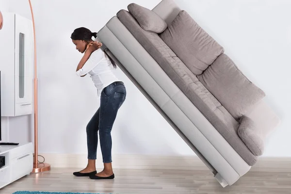 Wanita yang mencoba untuk memindahkan Sofa — Stok Foto