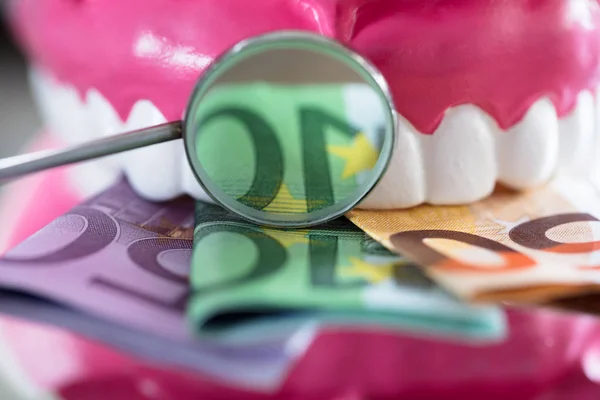 Prótesis dental con billete y lupa —  Fotos de Stock