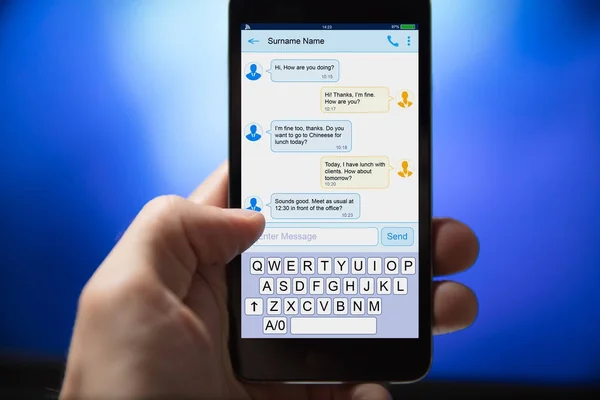 Nahaufnahme einer Person, die SMS von einem Mobiltelefon auf blauem Hintergrund sendet — Stockbild Person, die SMS sendet — Stockfoto