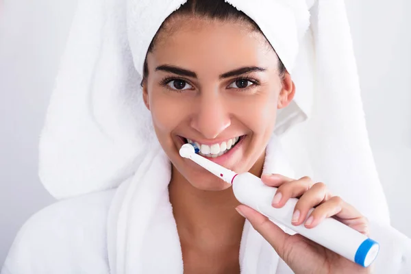 Vrouw in badjas tanden poetsen — Stockfoto