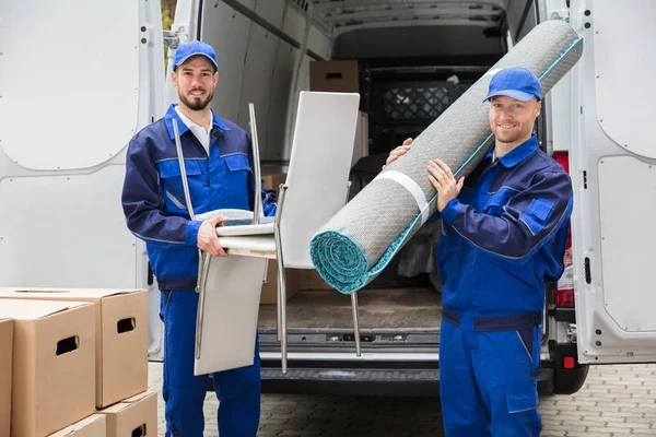 Hombres sosteniendo sillas y alfombras — Foto de Stock