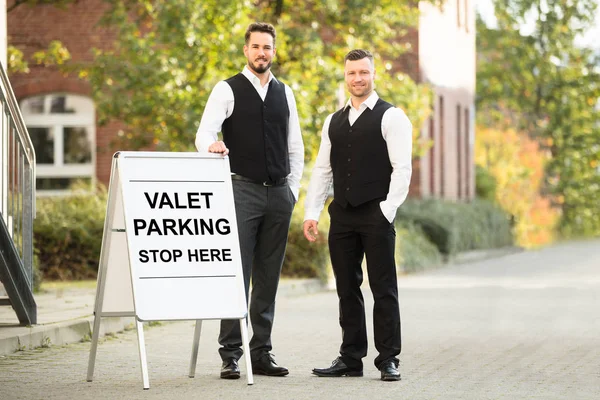 Male Valets Near Parking Sign