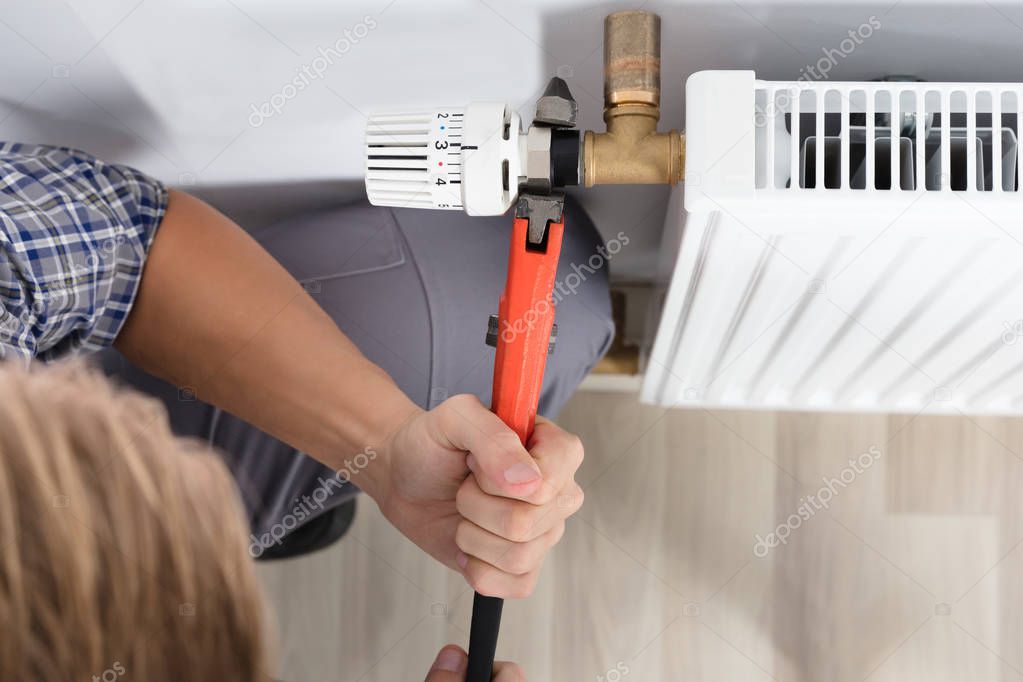 Male Plumber Fixing Thermostat 