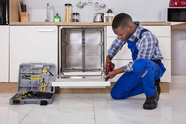 Reparador fixando máquina de lavar louça — Fotografia de Stock