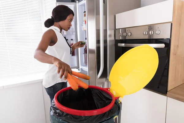 Donna gettando carota nel cestino — Foto Stock