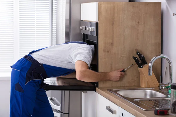 Electrician Repairing Oven With Screwdriver — Stock Photo, Image