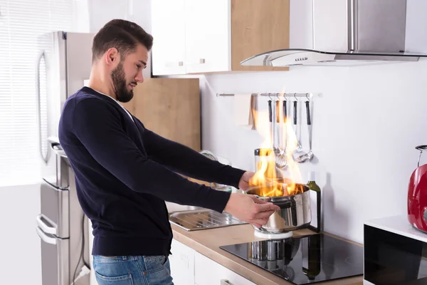 Mężczyzna, trzymając naczynie w ogniu — Zdjęcie stockowe