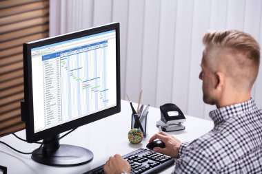 Ofisteki bilgisayarı kullanarak Gantt çizelgesinde çalışan bir iş adamının yakın plan fotoğrafı.