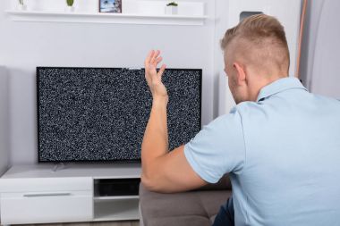 Televizyon sinyal önünde kanepede oturan sinirli adam
