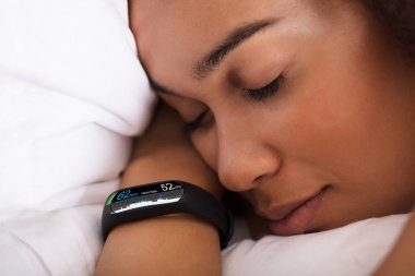Kalp atışı oranı gösterilen Smartwatch ile yatakta uyuyan kadın Close-Up
