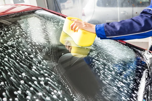 サービス ステーションでスポンジで車のフロント ガラスの清掃人の手 — ストック写真
